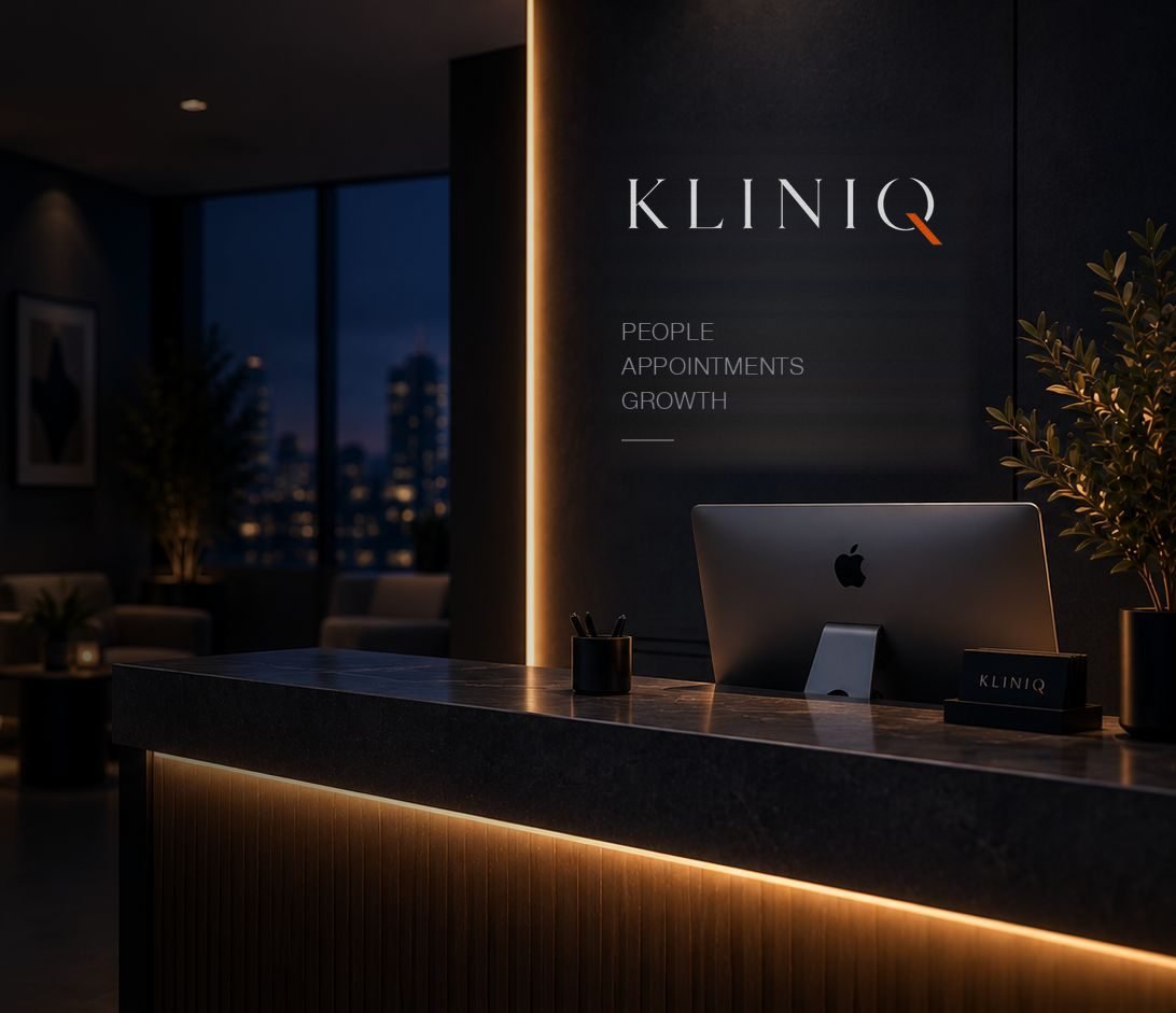 A reception desk at dusk under the KlinIQ wall, a monitor and appointment card on the stone counter